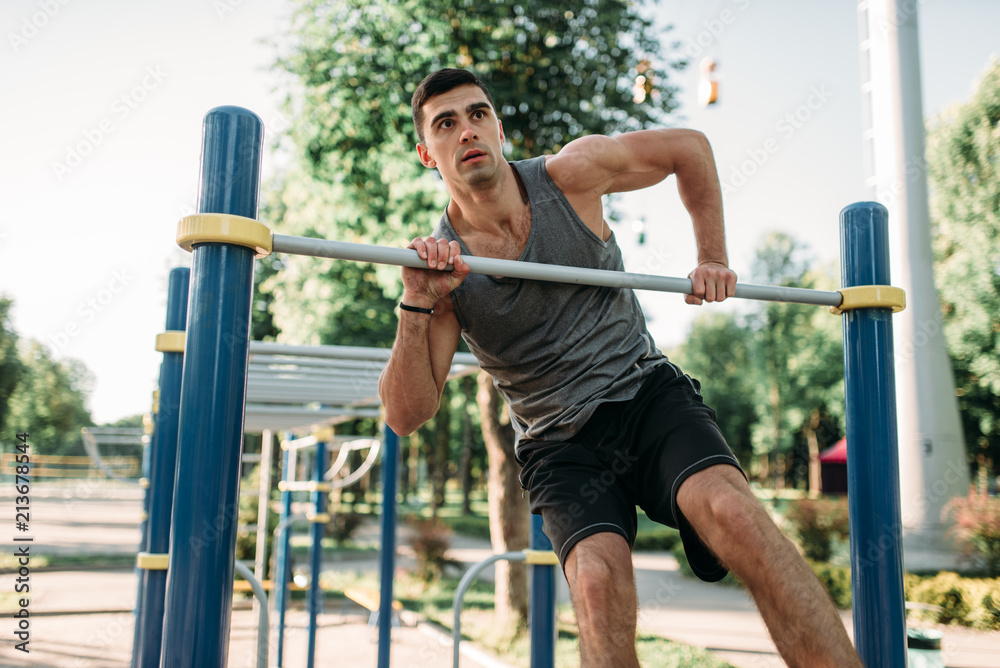 Man doing exercise on horizontal bar outdoor Man doing exercise on horizontal bar outdoor