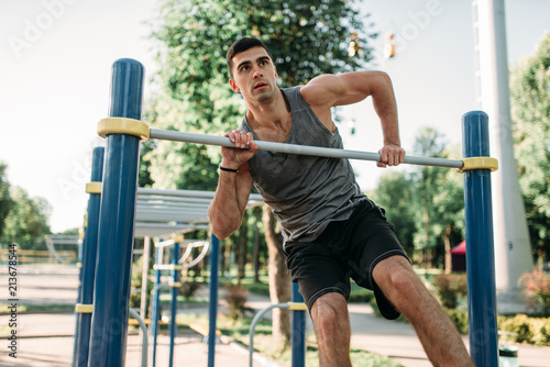 Man doing exercise on horizontal bar outdoor