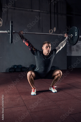 Young athlete lifting the barbell in gym. Gym training
