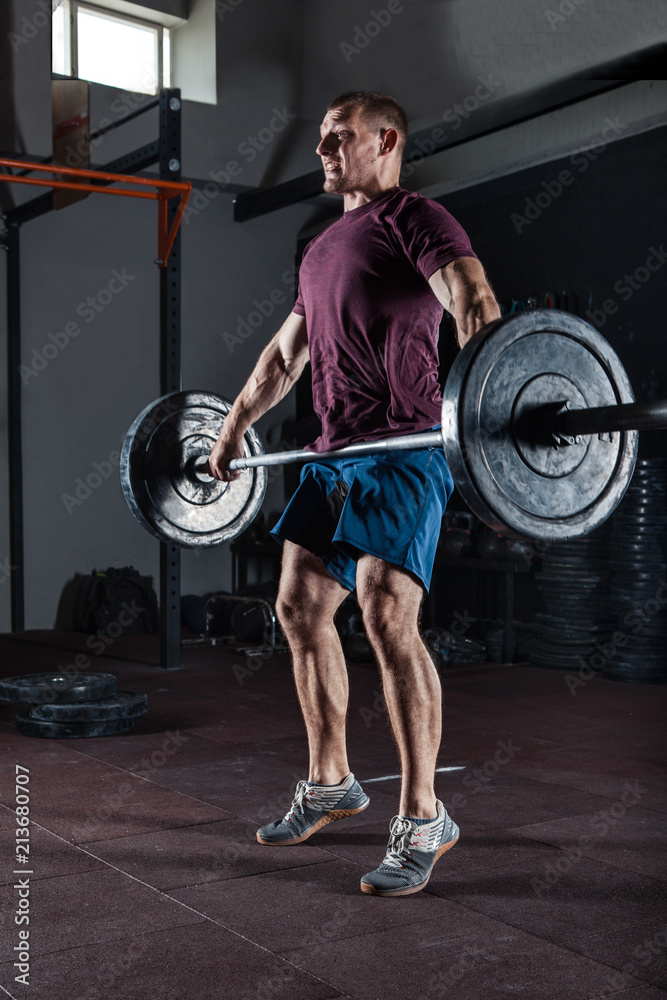 Young athlete lifting the barbell in gym. Gym training