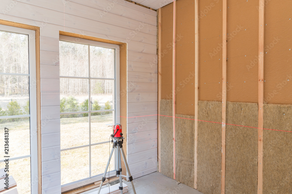 Fotografie Construction worker thermally insulating eco-wood frame house with wood fiber plates and heat-isolating natural hemp material