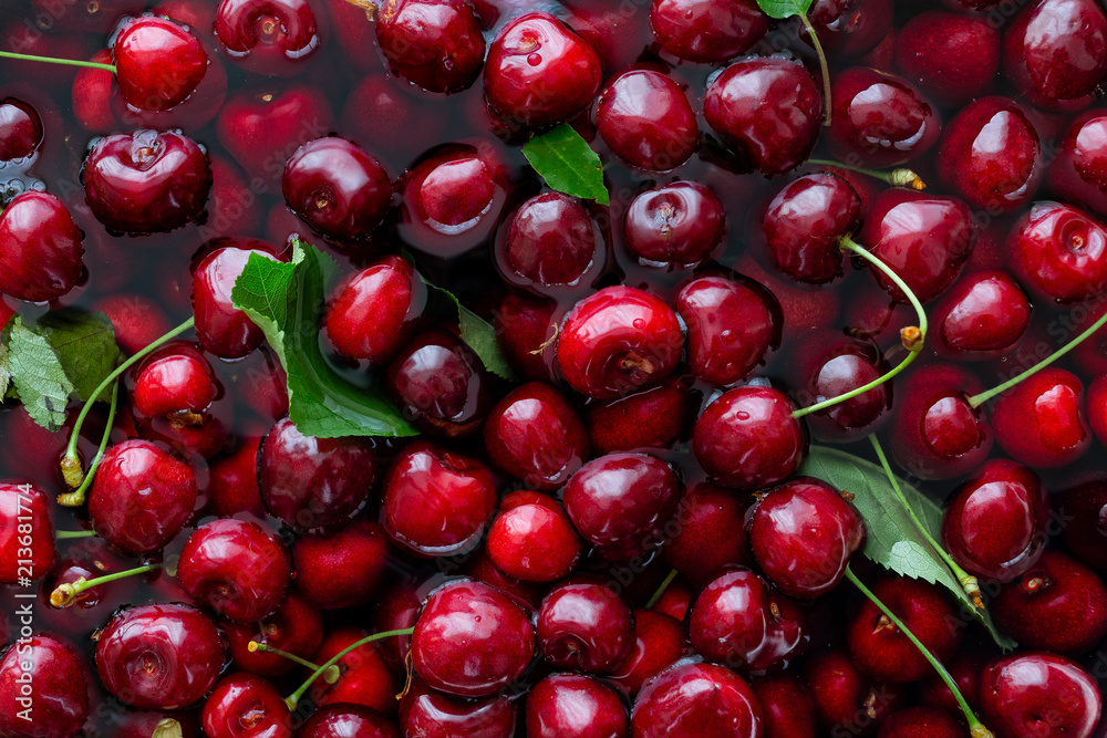 Background of freshly picked red cherries with leaves in water from above. Background of freshly picked red cherries with leaves in water from above.