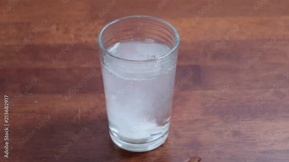 Dropping two asprin tablets into a glass of water Dropping two asprin tablets into a glass of water