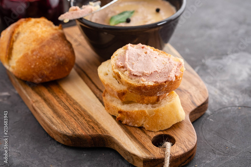 Homemade chicken liver pate or paste served with homemade bread and cranberry sauce over a rustic wooden board.