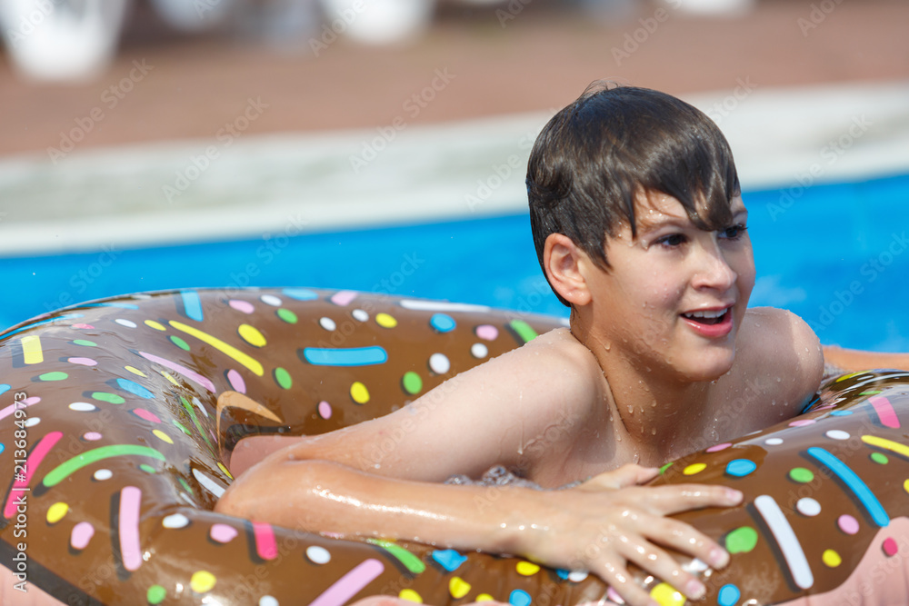 cute boy in inflatable ring - donut in the blue water in the pool ...