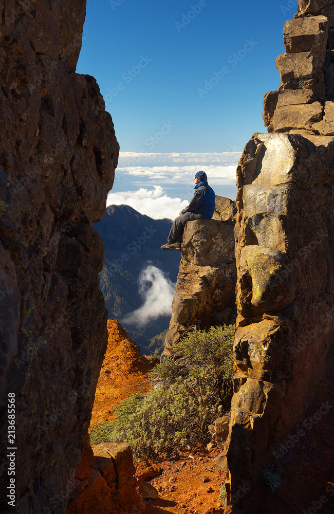 Resting man sitting on the rock above the crater Caldera de Taburiente, Island of La Palma, Canary Islands, Spain