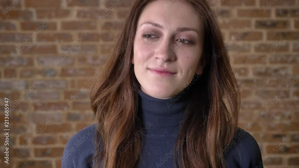 Brown hair girl with eyes full of tears is watching at camera, deep breath, brick background Brown hair girl with eyes full of tears is watching at camera, deep breath, brick background