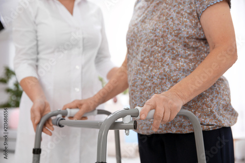 Senior woman with walking frame and caregiver at home, closeup