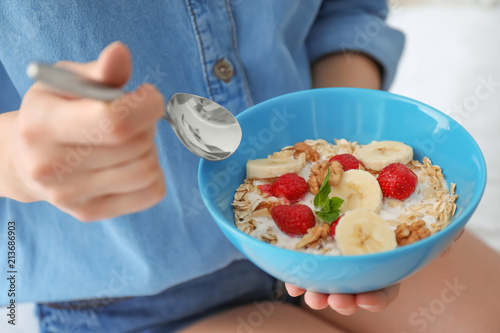 Woman eating delicious oatmeal with fruits, closeup. Healthy diet