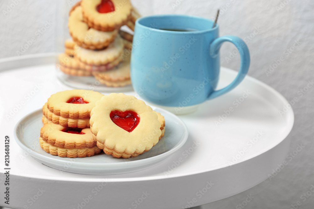 Traditional Christmas Linzer cookies with sweet jam and cup of tea on table Traditional Christmas Linzer cookies with sweet jam and cup of tea on table