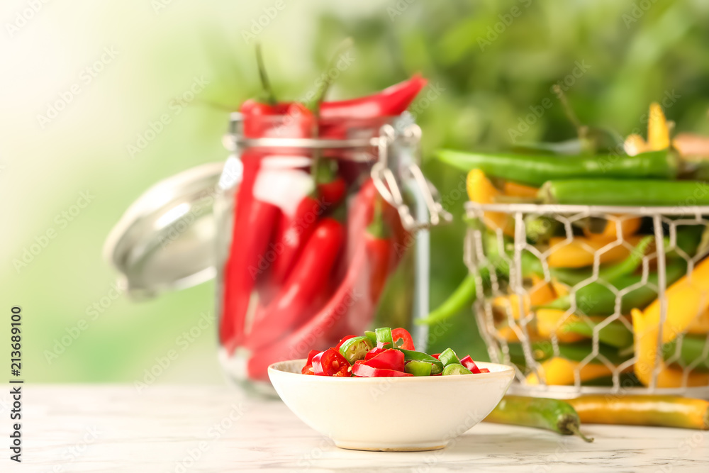 Bowl with cut chili peppers on table against blurred background Bowl with cut chili peppers on table against blurred background