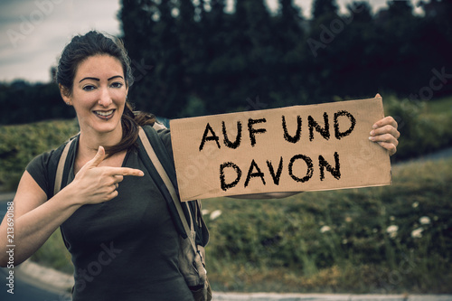 junge Tramperin mit Pappschild auf und davon photo