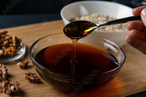 Healthy Breakfast ingredients: honey, walnuts, oatmeal on a dark background. Healthy diet. Close up. honey dripping from spoon