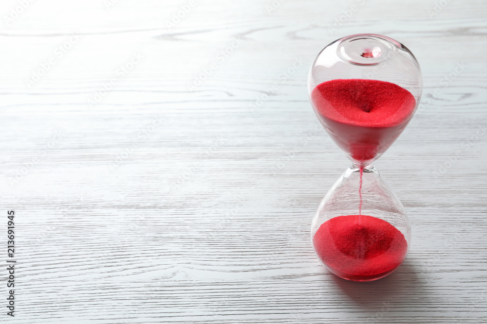 Hourglass with flowing red sand on wooden background. Time management - obrazy, fototapety, plakaty 