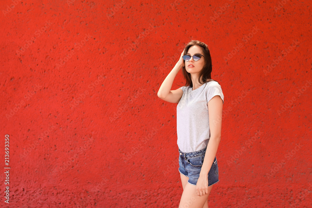 Young woman wearing gray t-shirt near color wall on street Young woman wearing gray t-shirt near color wall on street