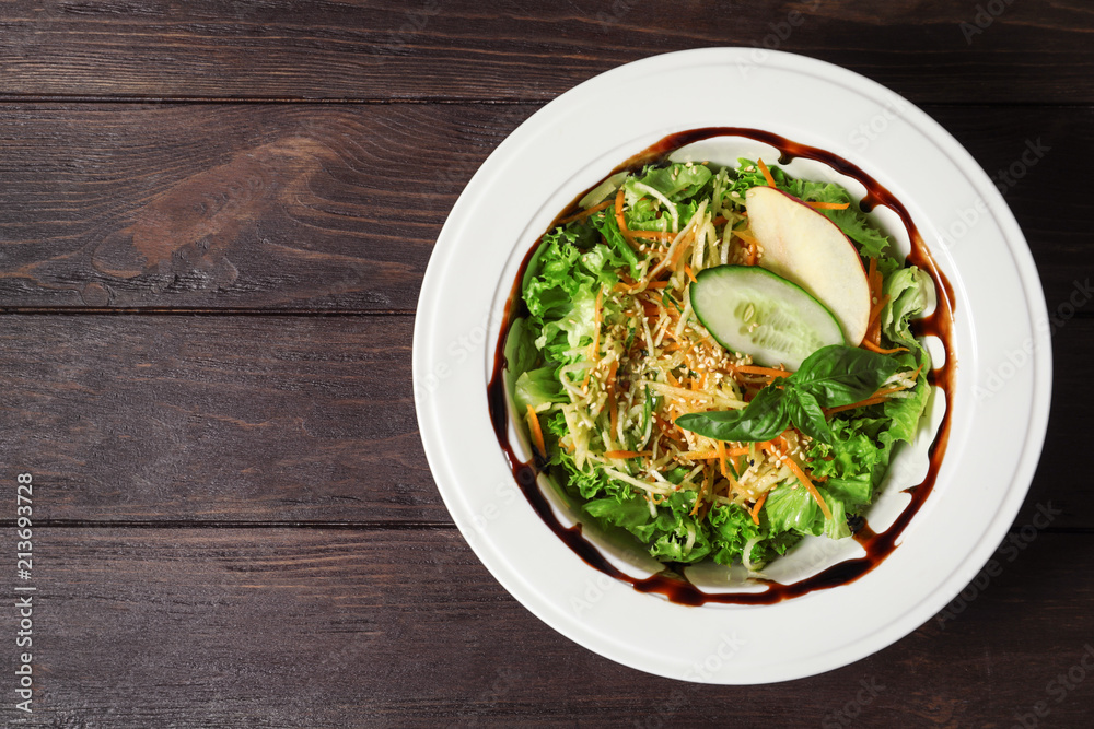 Plate with delicious fresh salad on table, top view Plate with delicious fresh salad on table, top view