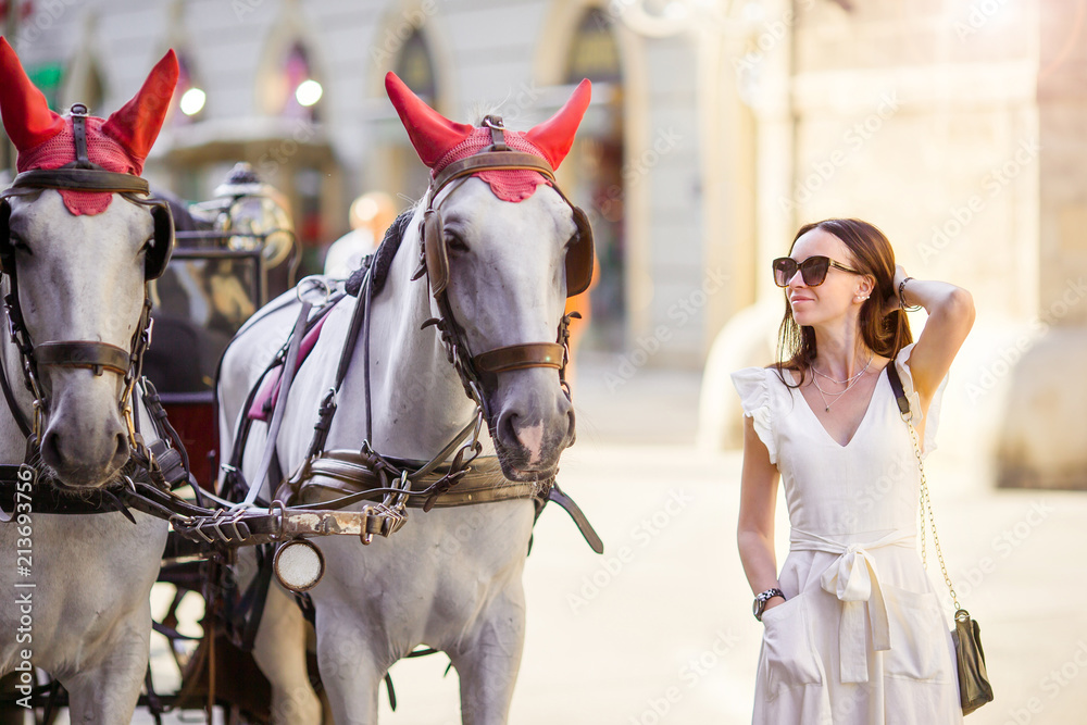 Tourist girl enjoying a stroll through Vienna and looking at the beautiful horses in the carriage