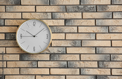 Stylish clock on brick wall. Time concept