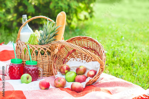 picnic basket, fruit, juice in small bottles, apples, milk, pineapple summer, rest, plaid, grass Copy space