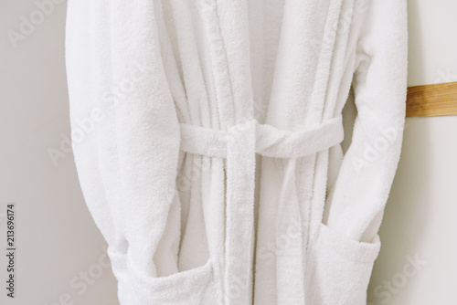 Pure white comfy cotton bathrobes on hangers. Concept of coziness and comfort. Relaxing at home or in a hotel.