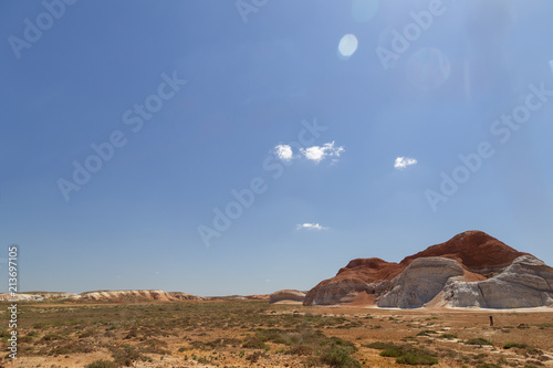 Multicolored red  orange and yellow single hill on the grass-covered steppe at sunny day in Eastern Kazakhstan