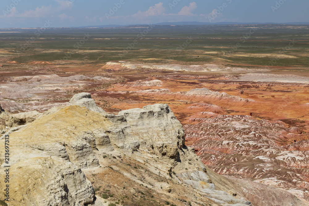 Obraz premium Aerial view on multicolored red, orange and yellow striped hills under the bright blue sky in Kiin-Kerysh (Valley of Spirits) Eastern Kazakhstan