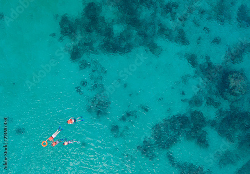 Beautiful sea view, shot by drones. People swim in the transparent sea between coral reefs. Aerial view of tourists swimming in beautiful clear sea water. 