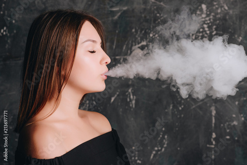 Beautiful girl exhaling cloud of smoke