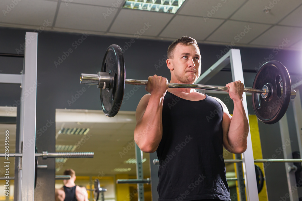 Powerful bodybuilder doing the exercises with barbell. Strength and motivation.