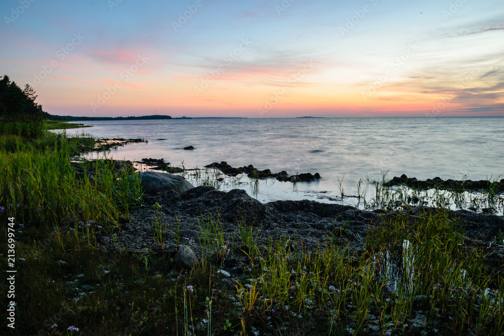 dramatic sunrise over the baltic sea with rocky beach and trees on the shore