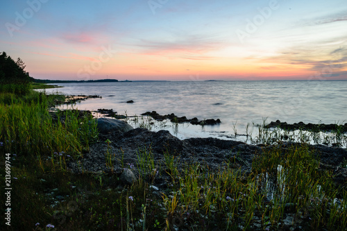Fototapeta Naklejka Na Ścianę i Meble -  dramatic sunrise over the baltic sea with rocky beach and trees on the shore