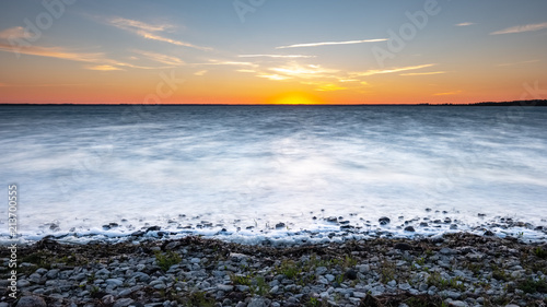 Fototapeta Naklejka Na Ścianę i Meble -  dramatic sunrise over the baltic sea with rocky beach and trees on the shore