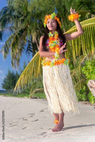Hula Hawaii dancer dancing on the beach with palms trees. Ethnic woman in costume dancer Hawaii hula dancing in a tropical nature.