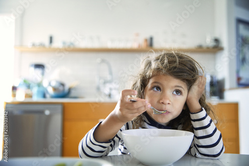 Girl looking away while eating food on table at home