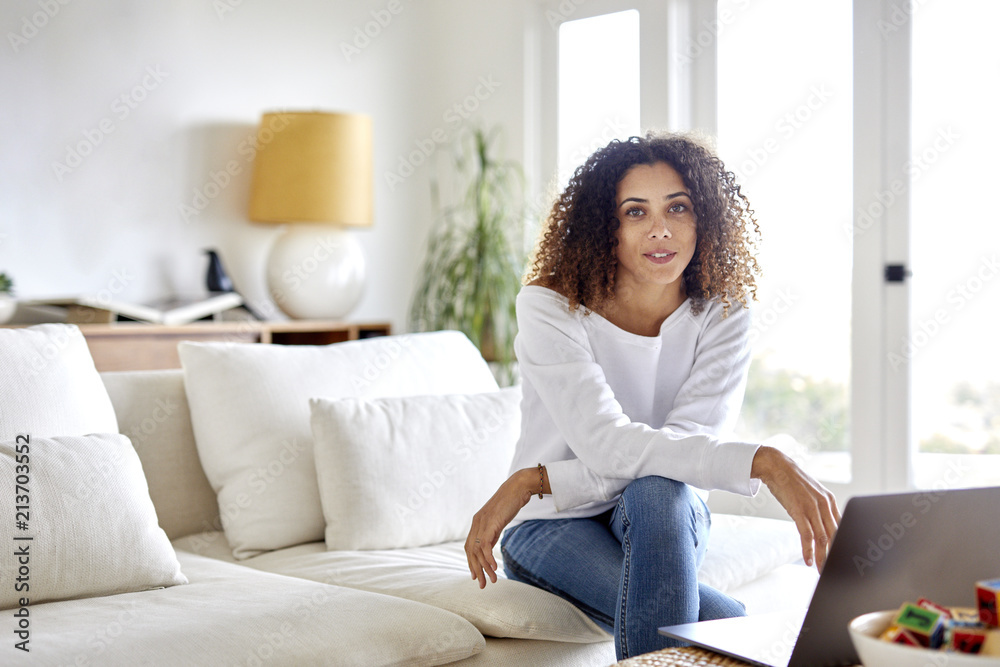 Portrait of woman with laptop computer sitting on sofa at home