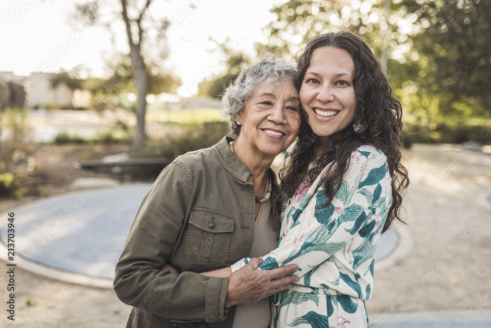 Happy mother and daughter embracing outdoors Happy mother and daughter embracing outdoors