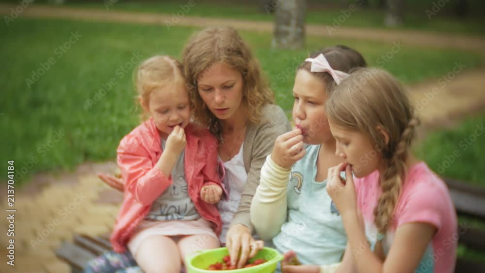 Funny children girl eating strawberries in park Funny children girl eating strawberries in park