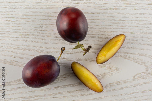 Group of two whole two slices of fresh violet-blue plum vibrant moyer variety flatlay on grey wood photo