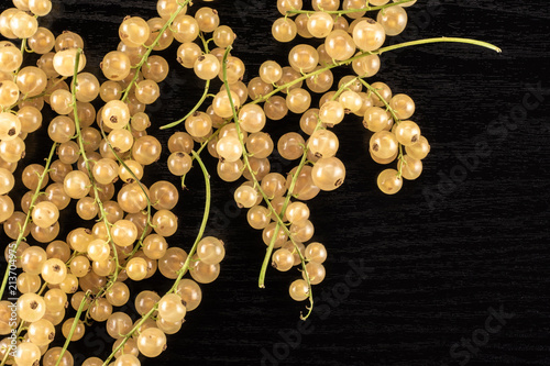 Lot of whole fresh white currant berry blanka variety left upper corner flatlay on black wood photo