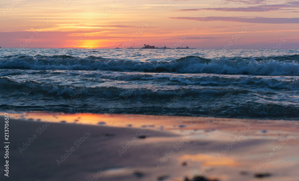 Obraz premium Sunset over the sea. Reflection of sunlight in the sea waves. Red sky in the rays of the sunset.