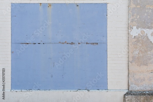Whitwashed old brick wall with blue borded up window