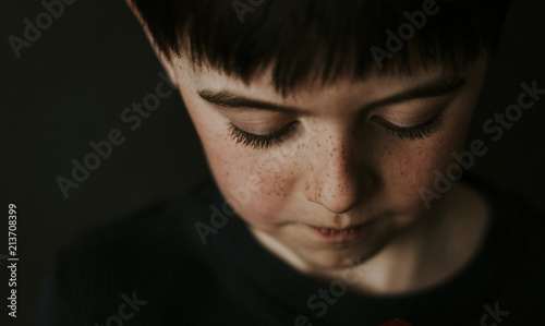 High angle close-up of boy with freckles over black background photo