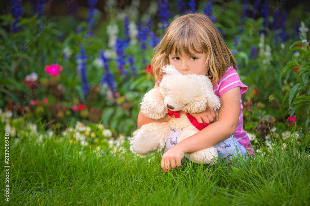 Adorable girl hugging her teddy bear in summer park Adorable girl hugging her teddy bear in summer park