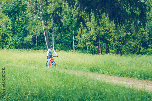 A cyclist in a helmet rides through the forest on a bicycle path