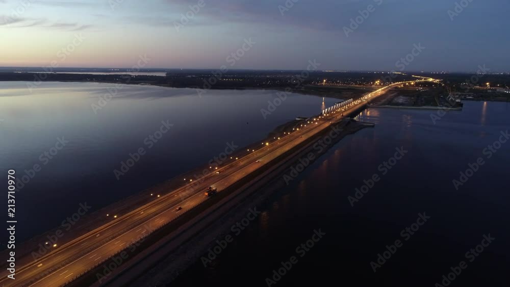 Dike with highlighted highway goes through sea to the city in the sunset dusk. Oudoors. Aerial. shot Dike with highlighted highway goes through sea to the city in the sunset dusk. Oudoors. Aerial. shot