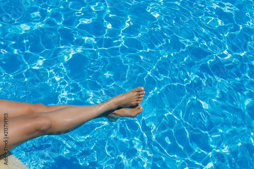 Beautiful sunburned female legs in a turquoise pool