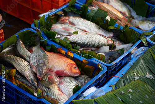 Sea fish on the floor with ice and palm leaves photo