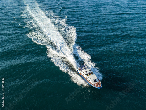 top view of fast speed motor boat in the open sea with splash and wave