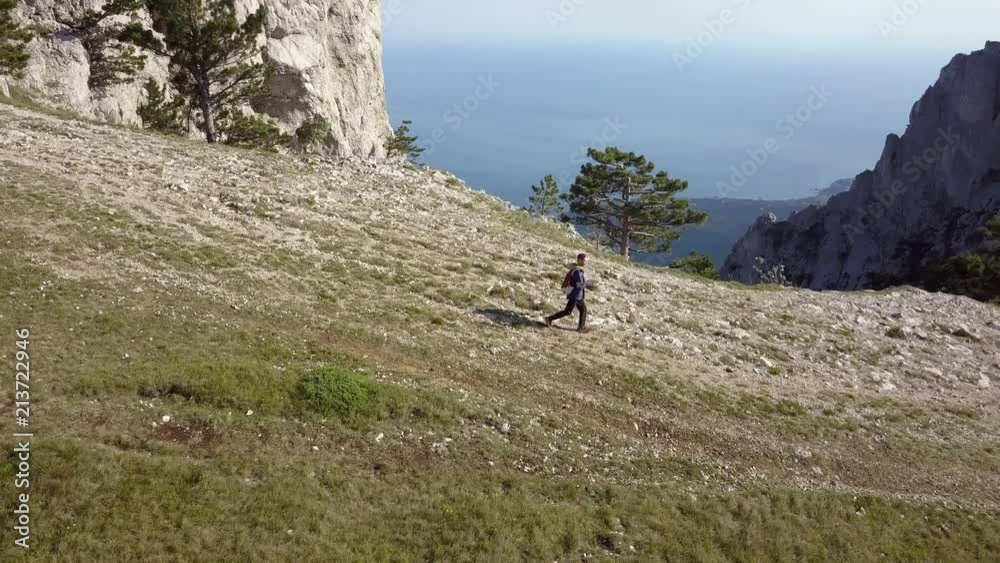 aerial flying view of young man in casual running on the mountain edge
