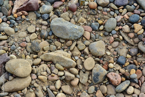 Stones with sand of different shapes of size and color. Gravel, cobblestones form a background. Material for construction